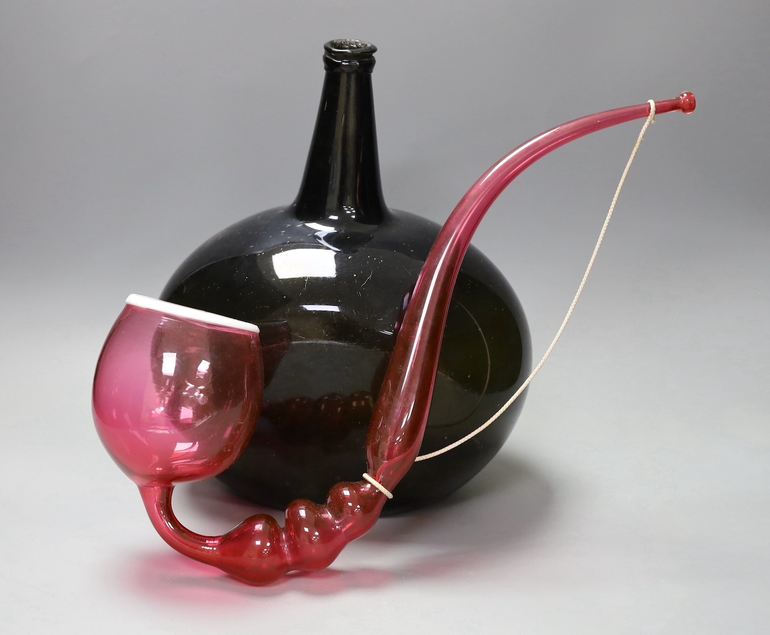 A large Georgian green glass bottle, 33 cm high and Nailsea-type ruby glass novelty pipe